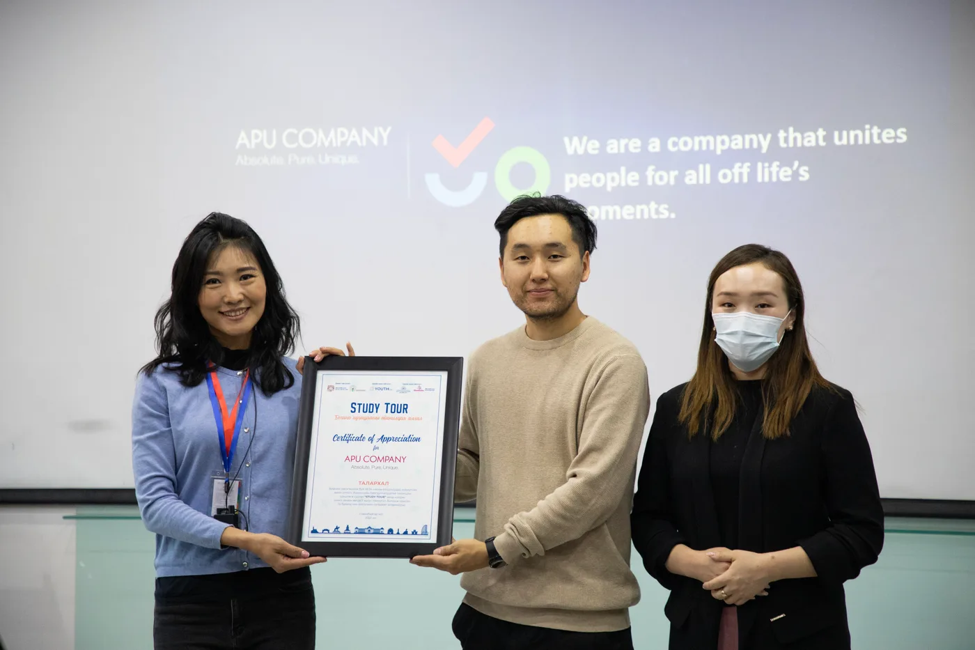 Three participants holding a certificate during the visit to APU Company