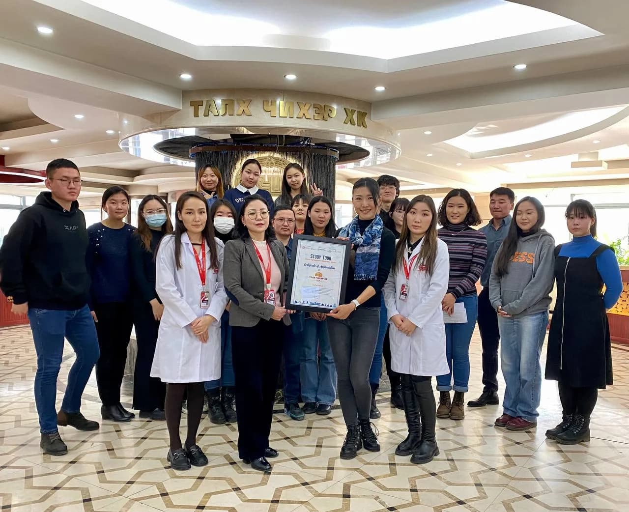 Participants in white coats with staff during the visit to Talkh Chikher